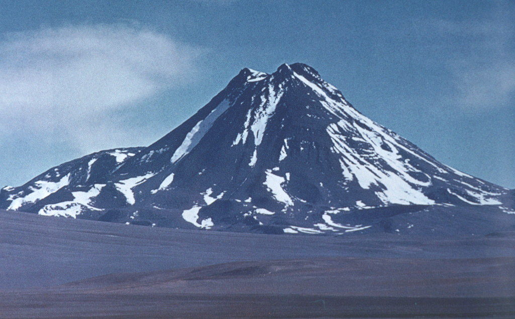 Acamarachi, an impressively steep-sided andesitic-dacitic volcano with slopes that reach about 45 degrees, towers above Laguna Aguas Calientes.  The 6046-m-high Acamarachi is the highest peak in this part of the northern Andes and lies at the SSE end of a small volcanic complex that extends from the neighboring volcano Colachi.  A poorly preserved summit crater and the absence of youthful flank lava flows suggest that Acamarachi was largely constructed in pre-Holocene times, although the summit lava flows may be younger. Photo by Oscar González-Ferrán (University of Chile).