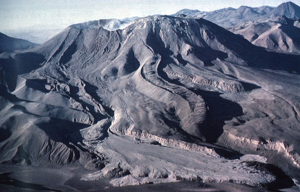 The lava flow with prominent lateral levees extending from the far left (eastern) side of the summit crater of Láscar is the Tumbres-Talabre lava flow.  This flow was erupted about 7100 years ago and descended 8 km down the NW flank of the volcano.  The distal part of the lava flow is overlain by light-colored pyroclastic-flow deposits in the foreground that originated during an eruption on April 19, 1993.  Another steep-sided viscous lava flow with pronounced lateral levees is visible in the center of the photo.  Photo by Carlos Felipe Ramírez, 1993 (courtesy of Oscar González-Ferrán, University of Chile).