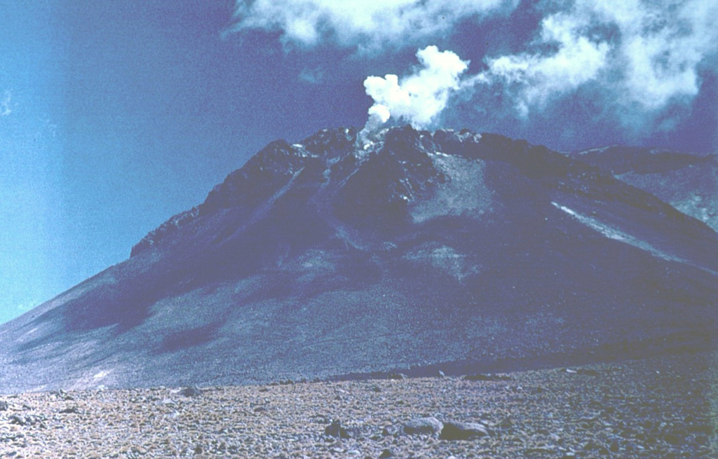 Steam pours from vigorous fumaroles near the summit of Volcán Ollagüe.  This massive 5868-m-high stratovolcano is capped by a large dacitic lava dome.  Collapse of the volcano produced a massive Pleistocene debris-avalanche deposit that extends to the west.  Active sulfur mines on the upper western and southern flanks are reached by a road that climbs to about 5500 m elevation.  Only increased fumarolic activity has been recorded at Ollagüe during historical time. Photo by Oscar González-Ferrán (University of Chile).
