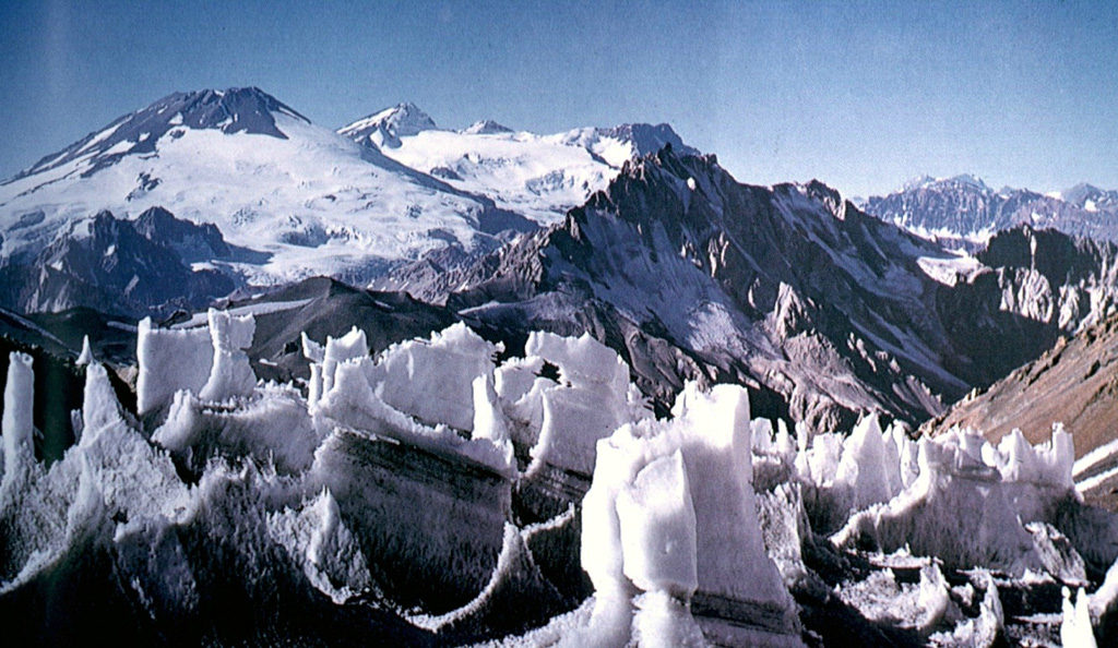 Volcán San José on the far left horizon rises to the north above ice pinnacles at the Nieves Negras pass on the Chile/Argentina border.  The summit of San José is formed by a cluster of six Holocene craters, pyroclastic cones, and blocky lava flows that lie within a series of elongated, 0.5 x 2 km wide nested craters.  Mild phreatomagmatic eruptions were recorded at San José in the 19th and 20th centuries.      Photo courtesy of Oscar González-Ferrán (University of Chile).