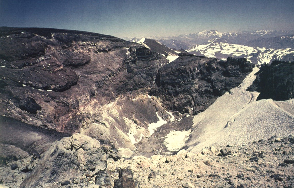 Alternating lava flows and pyroclastic deposits are exposed in the crater walls of Tinguiririca volcano.   Hydrothermally altered rocks are prominent in the lower parts of the crater walls. Photo by Wolfgang Foerster, courtesy of Oscar González-Ferrán (University of Chile).