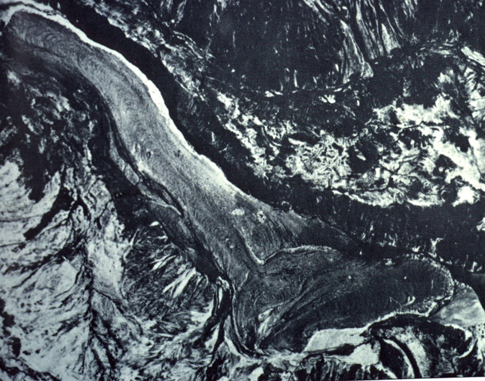 The 2048-m-high Mondaca lava dome (bottom center) produced a large youthful rhyodacitic lava flow that traveled north and dammed the Rio Lontue, eventually reaching 7 km to the NW (upper right).  This eruption may have taken place during historical time, possibly during the 19th century.  The solitary small Mondaca lava dome is located NNW of the Descabezado volcano complex and west of the Calabozos caldera.   Photo by Instituto Geográfico Militar, courtesy of Oscar González-Ferrán (University of Chile).