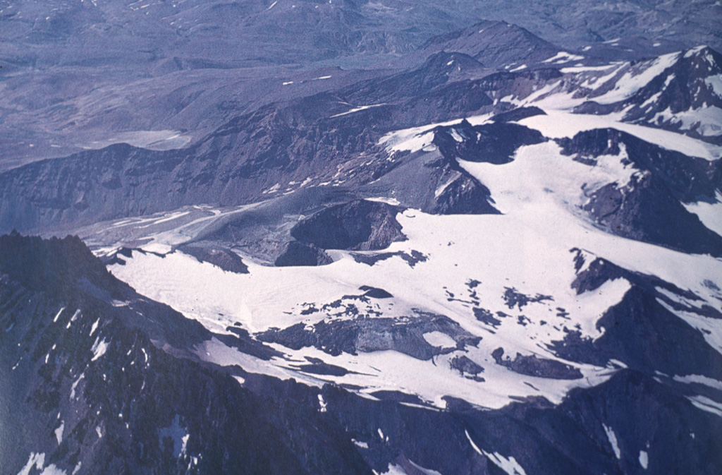 An aerial view from the NW overlooks Planchón-Peteroa, a complex volcano with several overlapping calderas.  In the left foreground is the caldera wall of Planchón volcano.  The crater complex of Peteroa is in the center, and Volcán Azufre lies at the upper right.  Activity began in the Pleistocene at Volcán Azufre, followed by formation of Volcán Planchón, 6 km to the north.  Volcán Peteroa has been active into historical time and contains a small steaming crater lake. Photo by Oscar González-Ferrán (University of Chile).