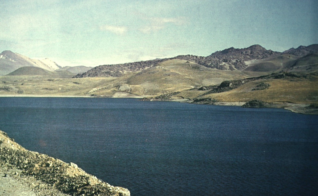 Pyroclastic cones and lava flows at the NW side of the Laguna del Maule volcanic center rise above the shore of the lake.  This cluster of small stratovolcanoes, lava domes, and pyroclastic cones covers an area of 15 x 20 km within a Pleistocene caldera.  Pleistocene and Holocene basaltic lava flows were erupted down the upper part of the Maule River valley and on all sides of the lake.   Photo by Oscar González-Ferrán (University of Chile).