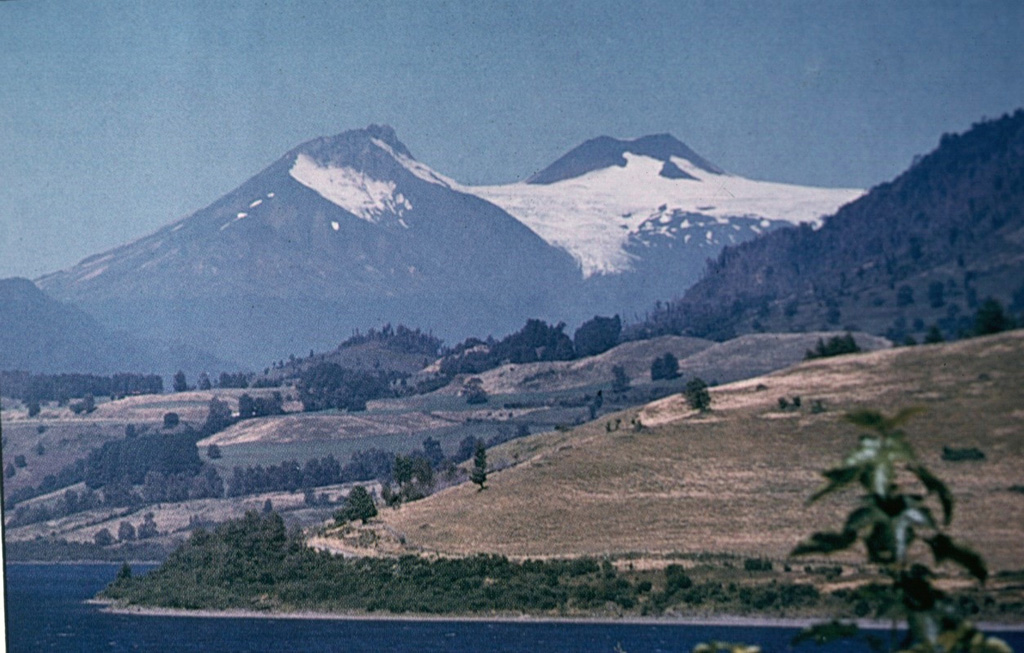 The compound Mocho-Choshuenco volcano, seen here from the SW, is composed of two glacier-covered stratovolcanoes post-dating a 4-km-wide caldera.  Choshuenco (left), was constructed during the late Pleistocene on the NW rim of the caldera.  The andesitic-to-dacitic, 2422-m-high El Mocho (center), is a small cone that grew within the caldera and has remained active into historical time. Photo by Oscar González-Ferrán (University of Chile).