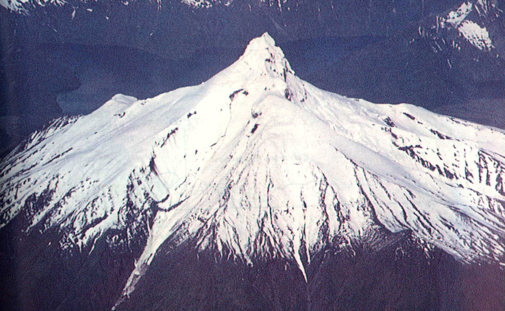 The dramatic summit spire of Volcán Corcovado is seen here in an aerial view from the south.  Two of a string of lakes on its eastern side appear in the background.  Corcovado, probably of late-Pleistocene age, is eroded by glaciers and surrounded by Holocene cinder cones.  Eruptions were reported in historical time from these flank cones.  Darwin observed activity from the Corcovado area in 1834, and an eruption was reported to have occurred in November 1835.     Photo by Oscar González-Ferrán (University of Chile).