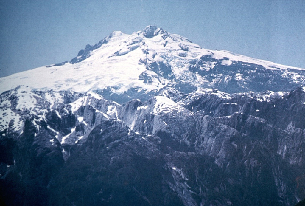 The western side of glacier-covered Monte Tronador volcano overlies rugged granitic peaks of the Northern Patagonian Batholith in the foreground.  Activity at the Tronador volcanic group, which straddles the Chile-Argentina border east of scenic Lake Todos los Santos, dates back to the early Pleistocene and ended during the mid-Pleistocene.  The only possible Holocene activity in the volcano group took place SSE of Monte Tronador, forming the post-glacial Fonck cinder cone and lava flow. Photo by Oscar González-Ferrán (University of Chile).