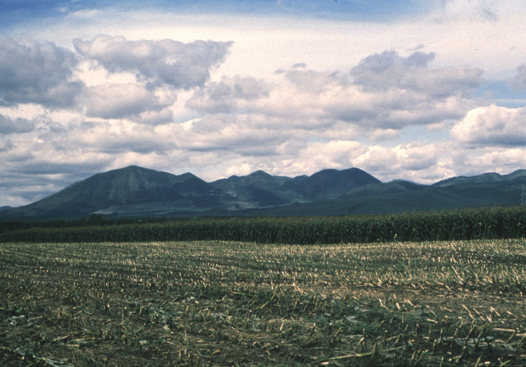 Shikaribetsu, seen here from the SE, consists of a group of lava domes W and S of Lake Shikaribetsu. The youngest domes were constructed along an ENE-WSW trend S of the lake. The largest dome, Higashi-Nupukaushi (left), was built at the SW end of a horseshoe-shaped crater, of which the NE rim forms the small peak right of the summit. Two or more large debris avalanche deposits extend to the S. Photo by Hiromitsu Yamagishi (Geological Survey of Hokkaido).