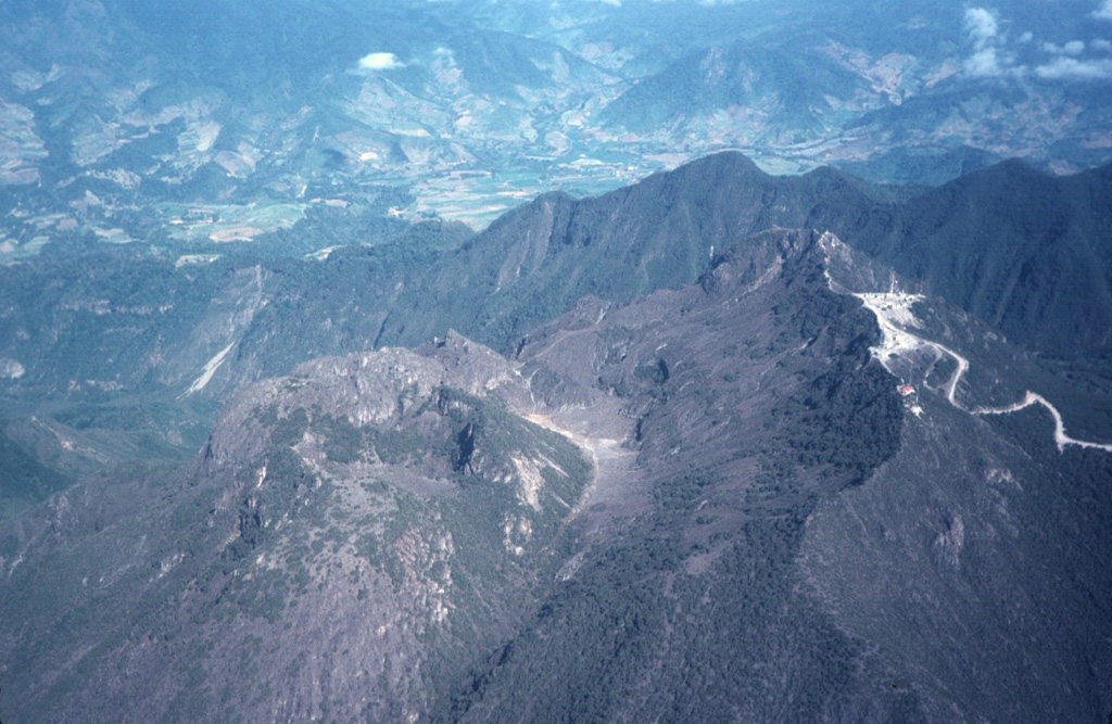 The Volcán Barú summit lava dome complex is seen here from the SE. The road to the right leads to communication towers at the summit. The ridge extending across the photo beyond the domes is the northern headwall of a large horseshoe-shaped collapse scarp.  Photo by Tom Casadevall, 1994 (U.S. Geological Survey).