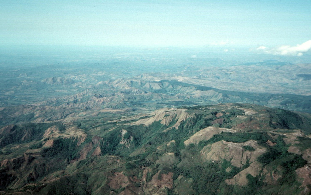 The topographic high point of the fault-bounded central horst of La Yeguada volcanic complex is Cerro el Castillo (right center).  It and Cerro Novillo at the lower right are part of older Miocene rocks uplifted in the horst.  Quaternary volcanism took place in the northern part of the horst, out of view to the right, about 220,000 years ago.  In the background are extensive Tertiary ignimbrite deposits of La Yeguada formation, some of which are thought to have originated from vents in the central horst. Photo by Tom Casadevall, 1994 (U.S. Geological Survey).