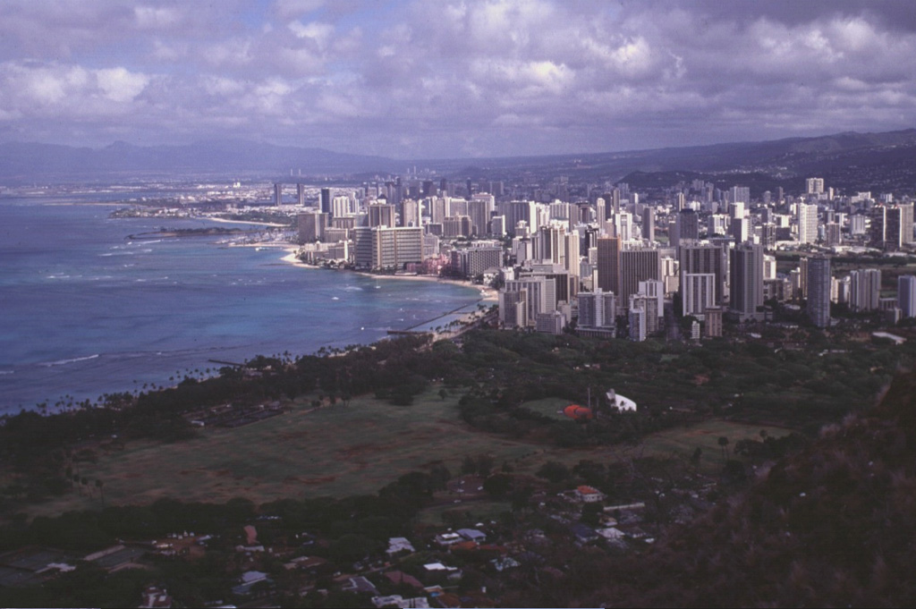The city of Honolulu, seen here from the rim of Diamond Head tuff cone, overlies the southern flank of the massive Koolau shield volcano, whose slopes rise to the right.  Koolau shield volcano was constructed during the Pliocene to Pleistocene and has been extensively eroded.  Diamond Head is part of the Honolulu Series, a group of tuff cones, cinder cones, and spatter cones constructed on the eastern flanks of Koolau following a long period of quiescence. Photo by Lee Siebert, 1998 (Smithsonian Institution).