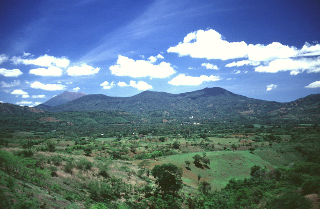 Chinameca volcano in the distance contains a 2-km-wide caldera, seen here from the north with the summit of San Miguel behind it to the left. A cluster of geothermal fields is located on the northern flank, surrounding the city of Chinameca. Photo by Carlos Pullinger, 1996 (Servicio Nacional de Estudios Territoriales, El Salvador).