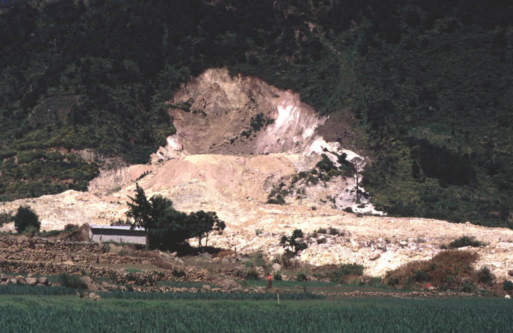 This photograph shows the source area of the 5 January 1991 Almolonga volcano Zunil geothermal field landslide. The slide damaged and buried the geothermal well ZCQ-4 within the Zunil 1 geothermal project. A small crater formed when debris that buried the well was ejected by hot water and steam that escaped from the damaged well. Photo by Carlos Pullinger, 1993 (Servicio Nacional de Estudios Territoriales, El Salvador).