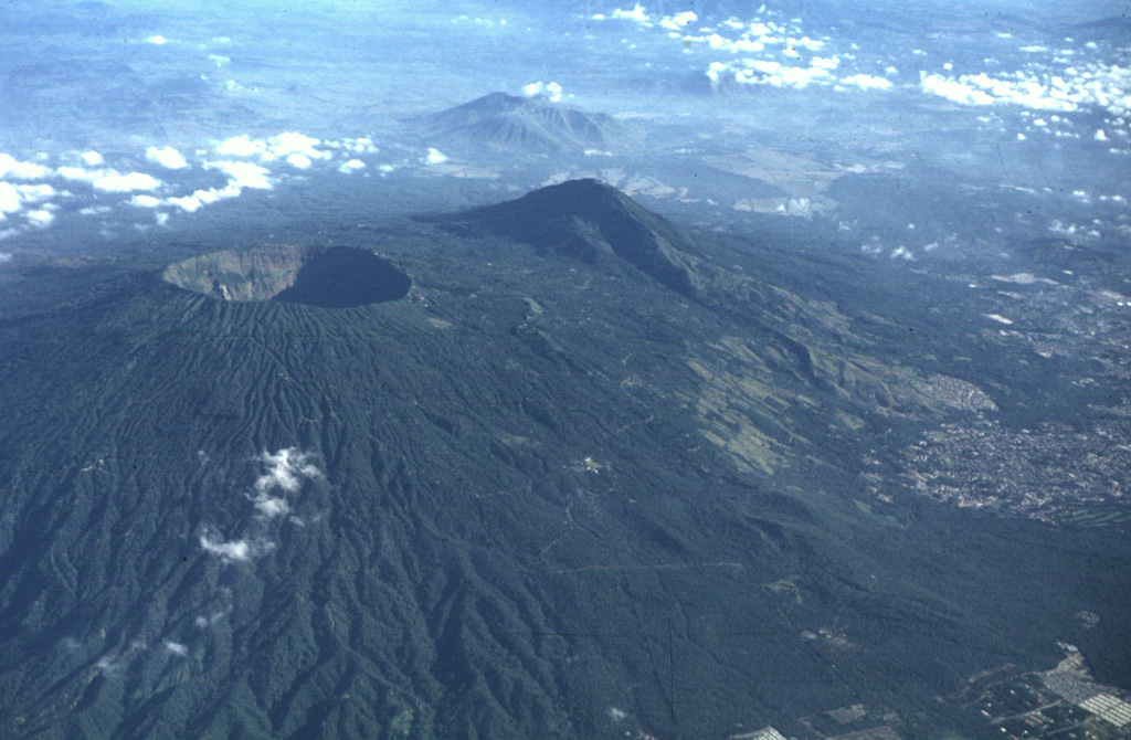 The 1.5-km-wide Boquerón crater formed during a major eruption about 1200 CE. The eruption produced a 0.3-0.5 km3 San Andrés Talpetate Tuff that went primarily to the west, and was accompanied by pyroclastic flows. The eruption was named after the San Andrés archaeological site, where it was first identified. The outskirts of the city of San Salvador extend up the flank to the right. Photo by Carlos Pullinger, 1996 (Servicio Nacional de Estudios Territoriales, El Salvador).