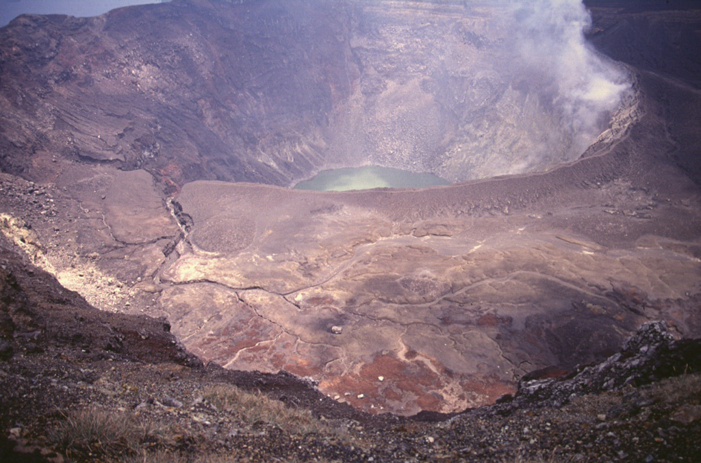 Santa Ana's active crater contains an acidic crater lake within the SE end of a series of four nested craters. This photo is taken from the northern rim of the second youngest crater and shows an older crater floor containing several small phreatomagmatic vents that formed during historical eruptions. Photo by Carlos Pullinger, 1996 (Servicio Nacional de Estudios Territoriales, El Salvador).