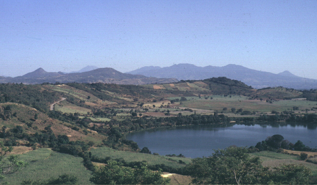 Laguna de Apastepeque in the foreground is one of several lake-filled maar craters in the Apastepeque volcanic field. The broad range in the distance to the right is the SE is the Tecapa massif. To the far right is the peak of Volcán Taburete. San Miguel volcano is in the midground to the left. Photo by Carlos Pullinger, 1994 (Servicio Nacional de Estudios Territoriales, El Salvador).