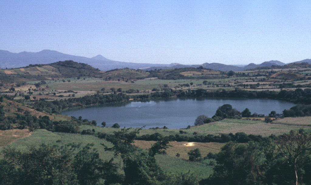 The Apastepeque volcanic field NE of San Vicente volcano consists of a dense cluster of about two dozen lava domes, scoria cones, and maars. Laguna de Apastepeque is seen here from the WNW with the Tecapa-San Miguel volcano group in the background. The visible walls of the 800-m-wide lake are only about 5 m high and the lake is approximately 50 m deep. Photo by Carlos Pullinger, 1996 (Servicio Nacional de Estudios Territoriales, El Salvador).