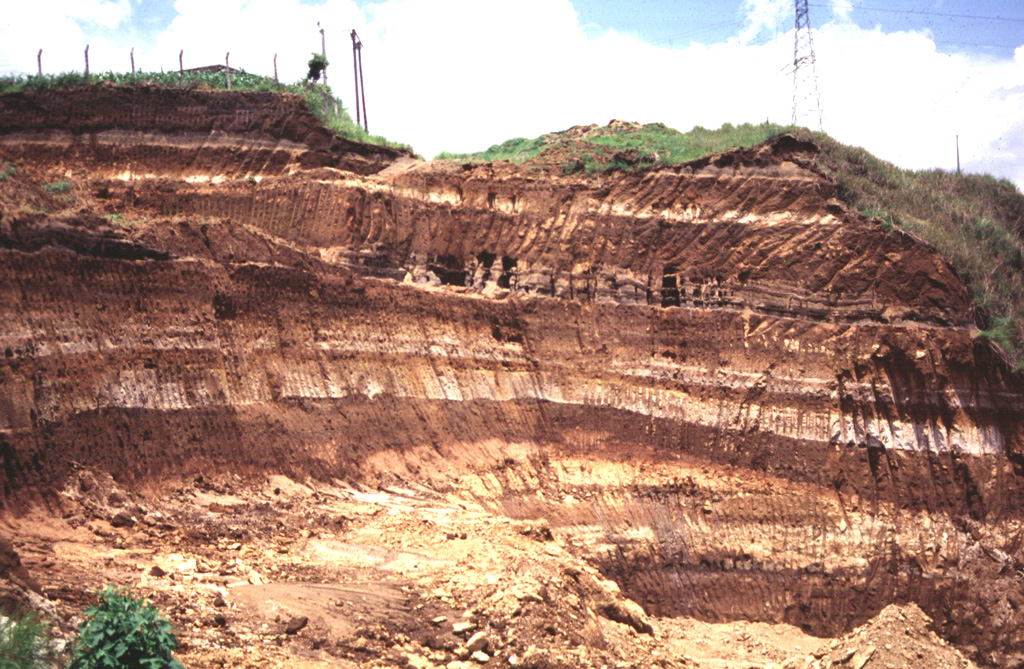 Light-colored rhyolite airfall pumice deposits from Coatepeque caldera are exposed in this quarry 20 km east of the caldera. These deposits were emplaced over much of SW El Salvador, and with the associated pyroclastic flow deposits have a volume of about 56 km3. The earlier biotite-bearing Arce deposits were produced during the largest eruption from Coatepeque about 72,000 years ago and are about 50 cmr thick at the Guatemalan border. The overlying Congo deposits originated during the second largest eruption of Coatepeque. Photo by Carlos Pullinger, 1996 (Servicio Nacional de Estudios Territoriales, El Salvador).