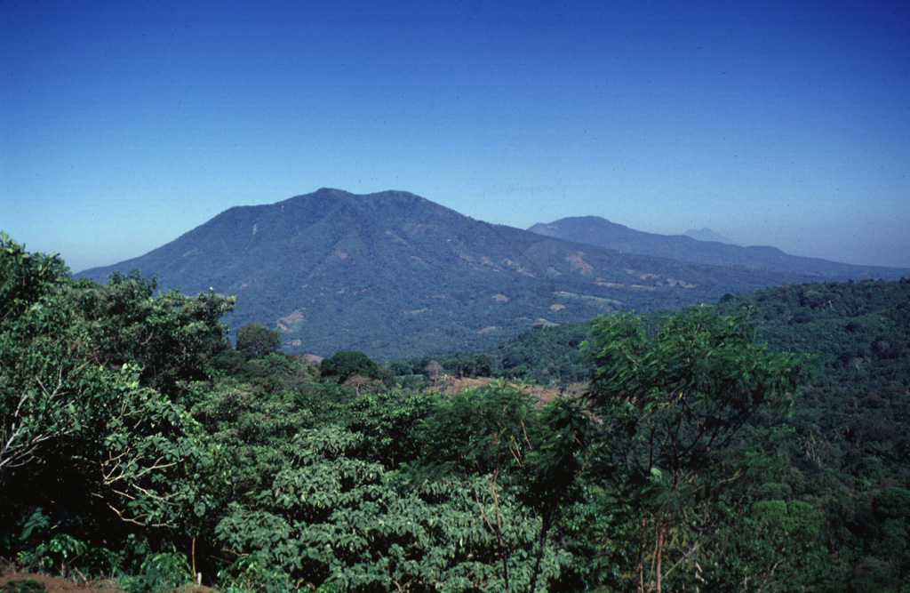 A westward view down the axis of a cluster of volcanoes between San Miguel and San Vicente volcanoes shows the eroded Pleistocene Cerro el Tigre volcano to the left and Tecapa to its right. San Vicente volcano is in the distance to the far-right. Photo by Carlos Pullinger, 1996 (Servicio Nacional de Estudios Territoriales, El Salvador).