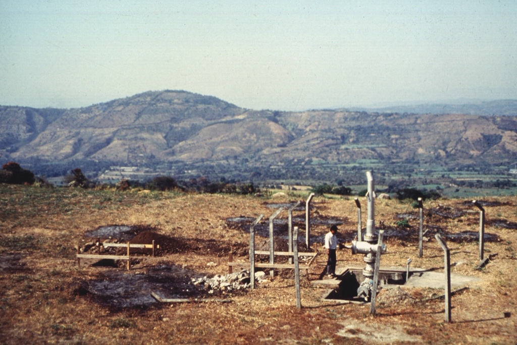 San Vicente is one of several volcanoes that have been the sites of geothermal exploration projects in El Salvador. The SV-1 well in the foreground is located on the northern flank. The low Cerro el Cerrón lava dome, part of the Apastepeque volcanic field, is to the NE on the left horizon. Photo courtesy of Comisión Ejecutiva Hidroeléctricia del Río Lempa (CEL), 1992.