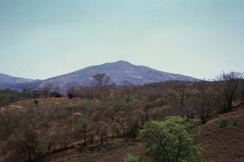 Cerro Masahuat is an eroded Pleistocene stratovolcano that was constructed SW of the San Diego volcanic field in western El Salvador.  The 1005-m-high volcano is seen here from the north and is surrounded on three sides by the Río Lempa, which lies beyond the ridge in the foreground. Photo by Giuseppina Kysar, 1999 (Smithsonian Institution).