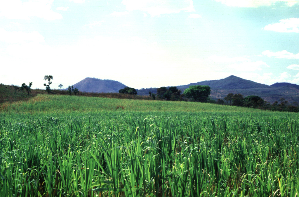 Cerro Redondo on the left and Picudo on the right are seen from the east across fields between the towns of Guazapa and Aguilares. These Pleistocene cones are part of the Pleistocene-to-Holocene Cerro Cinotepeque volcanic field. Photo by Giuseppina Kysar, 1999 (Smithsonian Institution).
