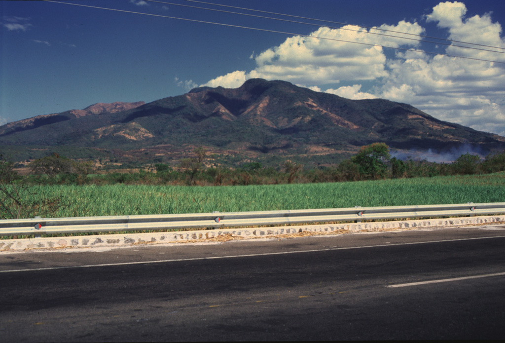 Guazapa is seen here from the west, 3 km NE of the town of Guazapa. This eroded Pleistocene cone is one of the largest of the interior valley of El Salvador. Deep erosional valleys have formed down the flanks, and younger cones and lava flows are found around its base. Photo by Giuseppina Kysar, 1999 (Smithsonian Institution).