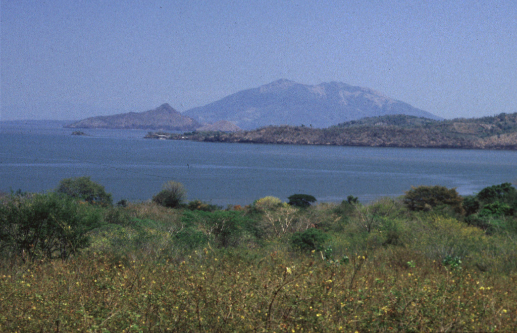 Zacate Grande volcano, seen here from Punta el Chiquirín at the eastern tip of El Salvador, forms a low 7 x 10 km wide island across a narrow strait from the end of a peninsula extending into the Gulf of Fonseca.  At least seven satellitic cones are located near the base of the 640-m-high dissected basaltic stratovolcano.  Some of these, including the symmetrical cone of Isla Gueguensi, are of probable Holocene age.  The northern tip of the Salvadoran island of Zacatillo forms the ridge in the center of the photo. Photo by Rick Wunderman, 1999 (Smithsonian Institution).