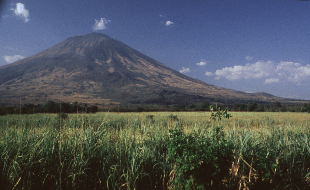 San Miguel is one of the most prominent volcanoes in El Salvador.  Its southern slopes, seen here, rise more than 2000 m above the farmlands on the Pacific coastal plain.  Both summit and flank vents have been active during historical time.  The dark-colored lava flow at the right-center was erupted from a SE-flank vent in 1819. Photo by Rick Wunderman, 1999 (Smithsonian Institution).