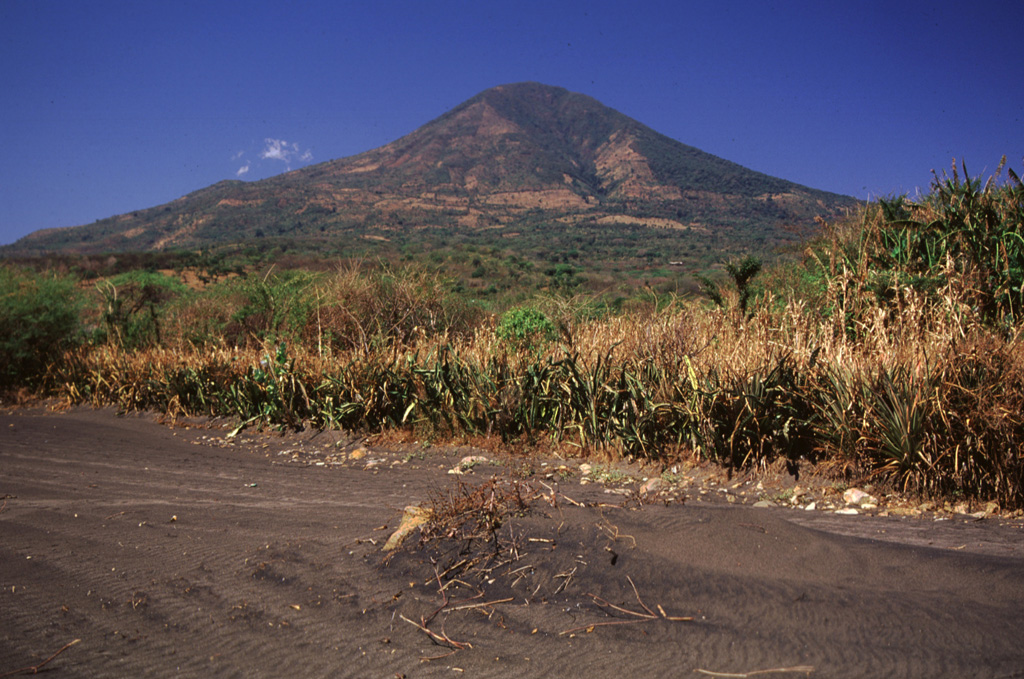 Conchagua volcano has a conical profile when seen from the NE near Punta el Chiriquín.  The volcano actually has a much more complex structure than seen here and has been extensively eroded.  It has two principal summits.  The eastern summit, Cerro de La Bandera, seen in this view, appears morphologically more youthful and is less dissected than Cerro del Ocote, which forms the 1225 m high point of the volcanic complex.   Photo by Rick Wunderman, 1999 (Smithsonian Institution).