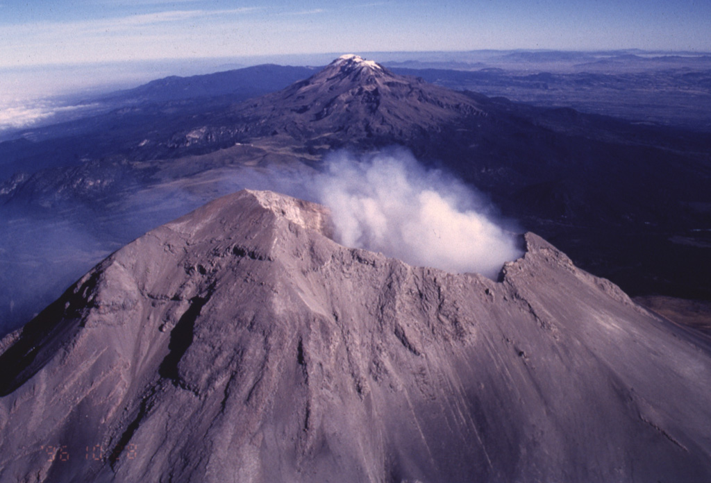 The Sierra Nevada east of the Valley of Mexico is a N-S-trending volcanic chain that runs perpendicular to the E-W trend of the Mexican Volcanic Belt. As with other transverse volcanic chains such as Cántaro-Colima and Cofre de Perote-Orizaba, the volcanic features in the Sierra Nevada range are younger towards the south. The broad forested volcanoes of Tláloc and Telapon in the distance are Pliocene in age, Iztaccíhuatl in the center is largely Pleistocene, and Popocatépetl in the foreground has been historically active. Photo by José Macías, 1996 (Universidad Nacional Autónoma de México).