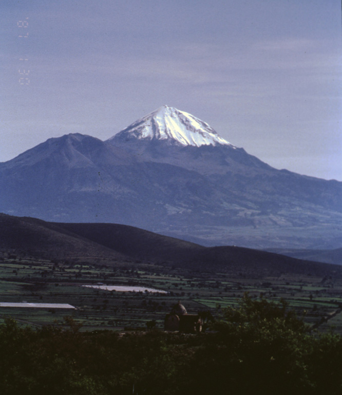 Pico de Orizaba, also known as Citlaltépetl ("Mountain of the Star")  is seen here from the south. The snow-free peak to the left is Sierra Negra, a Pleistocene volcano that was active simultaneously with Orizaba. These volcanoes mark the southernmost extent of the Cofre de Perote-Pico de Orizaba volcanic chain. Photo by José Macías, 1996 (Universidad Nacional Autónoma de México).