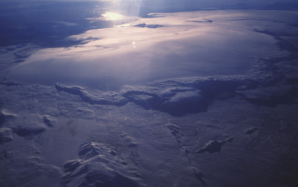 Hveravellir central volcano occupies the northeast section of the massive Langjökull icecap, which is seen here in an aerial view from the north with Hvítárvatn lake on the opposite side reflecting the sun. A summit caldera lies beneath the ice. An approximately 100-km-long fissure system extends to the north and southwest of Hveravellir, with numerous small shield volcanoes and lava flows. Photo by Oddur Sigurdsson, 1990 (Icelandic National Energy Authority).