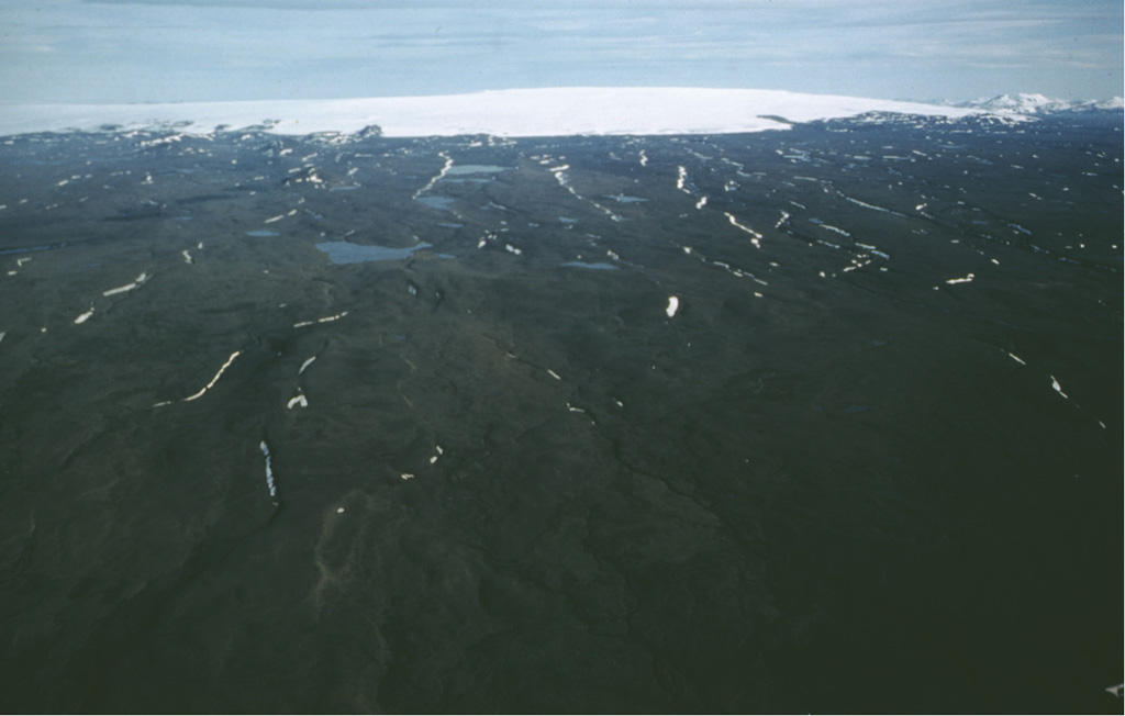 The broad Hofsjökull volcano lies beneath the western part of the massive Hofsjökull icecap. A caldera 7-8 km wide is beneath about 700 m of ice to the right of the high point in this view from the NNW. Lava flows are found to the south, east, and north of this central volcano. The rugged ice-covered peak at top right is the Kerlingarfjöll edifice. Photo by Oddur Sigurdsson, 1978 (Icelandic National Energy Authority).