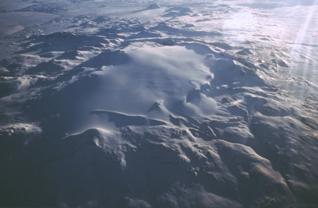 The Tungnafellsjökull central volcano lies immediately to the NW of the massive Vatnajökull icecap. The ~ 4 x 9 km summit caldera is largely filled by the Tungnafellsjökull glacier (center). An ice-free caldera to the SE, Vonarskarð, measures about 8 km in diameter; the caldera rim is visible in this image as a ridge at top left. Photo by Oddur Sigurdsson, 1986 (Icelandic National Energy Authority).