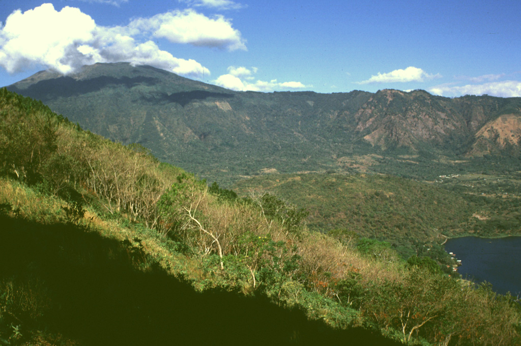 Santa Ana is seen here from the east on the rim of Coatepeque caldera. The eastern rim of Santa Ana's summit crater was breached and produced the gently sloping deposits extending towards the caldera lake to the lower right. The NW wall of the caldera in the background cuts into the flanks of Santa Ana. This SW part of Coatepeque caldera formed about 57,000 years ago during the eruption of about 16 km3 of rhyolite pumice and pyroclastic flow deposits. Photo by Lee Siebert, 1999 (Smithsonian Institution).
