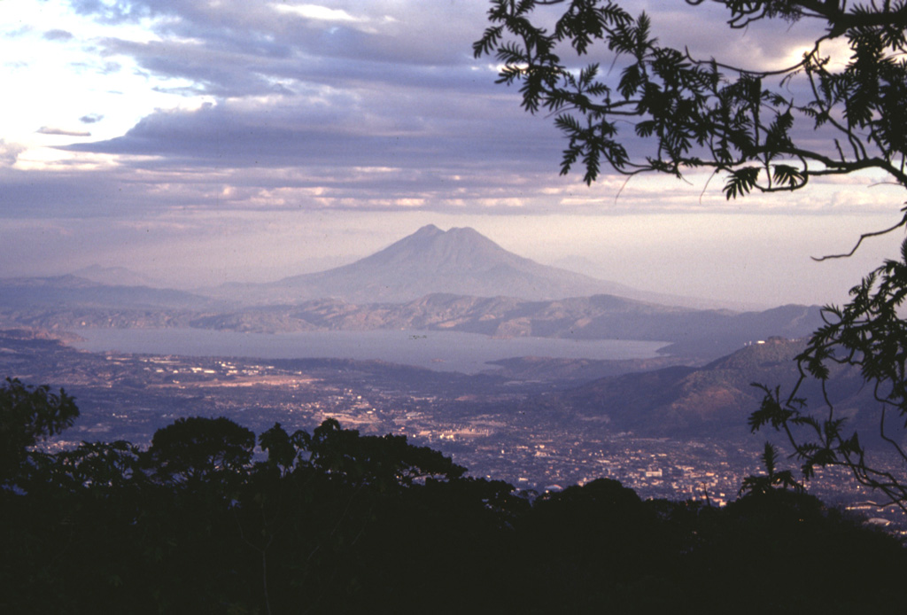 Lake Ilopango occupies the Ilopango caldera immediately east of the capital city of El Salvador, seen in the foreground. This view is from San Salvador volcano with San Vicente volcano in the background. The caldera formed during four major eruptions, the last of which was about 1,500 years ago. This eruption deposited ash and pumice over much of central and western El Salvador. Photo by Paul Kimberly, 1999 (Smithsonian Institution).