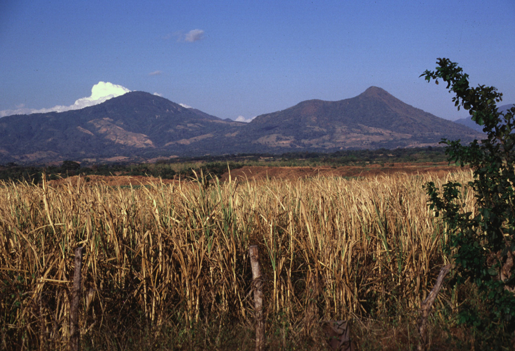 The Tecapa volcanic complex (left) and Volcan Taburete (right) are separated by a 800-m-high saddle.  They are seen here from the SW rising more than 1100 m above the Pacific coastal plain and lie at the eastern end of a volcanic chain reaching to San Miguel volcano.  A relatively young lava flow is found on the southern flank of Taburete volcano, although its age is not known precisely.  Fumarolic activity continues at Tecapa, the site of a major geothermal project. Photo by Lee Siebert, 1999 (Smithsonian Institution).