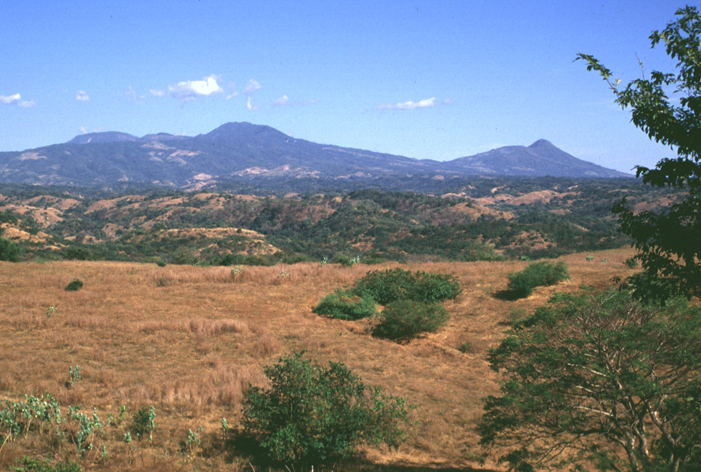 The Tecapa volcanic complex (left) and Volcán Taburete (right) rise to the east of the Río Lempa, which is hidden beyond the slope in the foreground. They are at the western end of the 40-km-long Tecapa-San Miguel volcano cluster in eastern El Salvador. Ignimbrites from a caldera-forming eruption at Tecapa were emplaced beyond the Río Lempa. Photo by Lee Siebert, 1999 (Smithsonian Institution).
