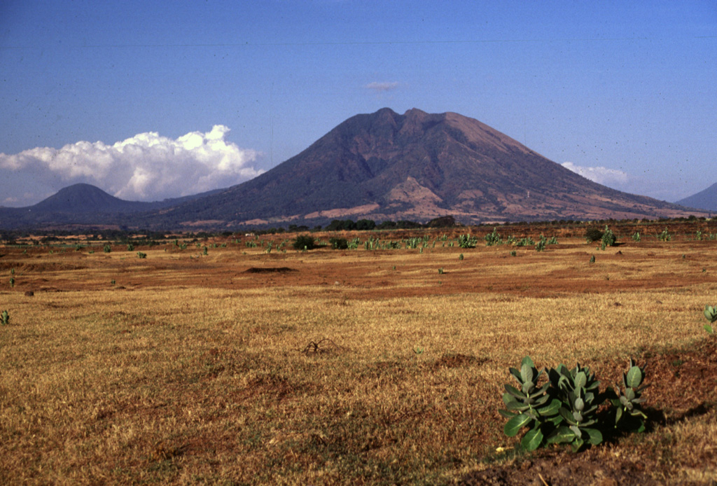 Usulután rises above the Pacific coastal plain at the SE end of a cluster of volcanoes between San Vicente and San Miguel. Several valleys have formed on the flanks of, including the one seen in this view of the SW flank. The rounded peak to the left is Cerro Oromontique on the flank of El Tigre volcano. Photo by Lee Siebert, 1999 (Smithsonian Institution).