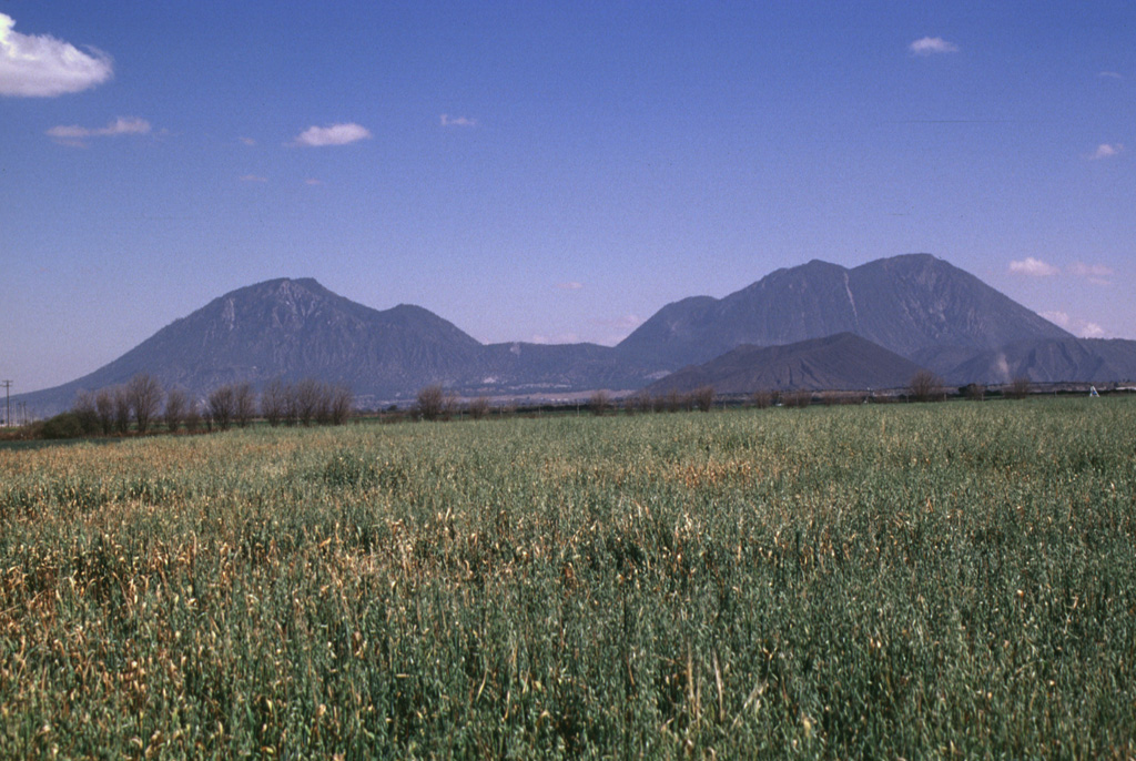 The most prominent features of the Serdán-Oriental volcanic field are the two Las Derrumbadas lava domes. The NW (left) and SE (right) domes are of similar height and lithology and rise about 1 km above their bases. The Serdán-Oriental is a broad closed basin at the eastern end of the Mexican altiplano containing lava domes, tuff rings, lava flows, and scoria cones of late-Pleistocene to Holocene age. Several of the tuff rings, such as Laguna Atexcac and Laguna Alchichica, contain crater lakes. Photo by Lee Siebert, 1997 (Smithsonian Institution).