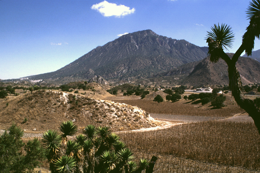 The NW-most of the two Las Derrumbadas lava domes is surrounded by hummocky debris avalanche deposits such as those in the foreground, that were produced by repeated collapse of the domes. The hummocks contain mixtures of rock types, including pyroclastic surge deposits, Cretaceous limestones, lacustrine sediments, and banded obsidians. These are thought to have originated from a former tuff ring that surrounded the lava domes. Photo by Lee Siebert, 1997 (Smithsonian Institution).