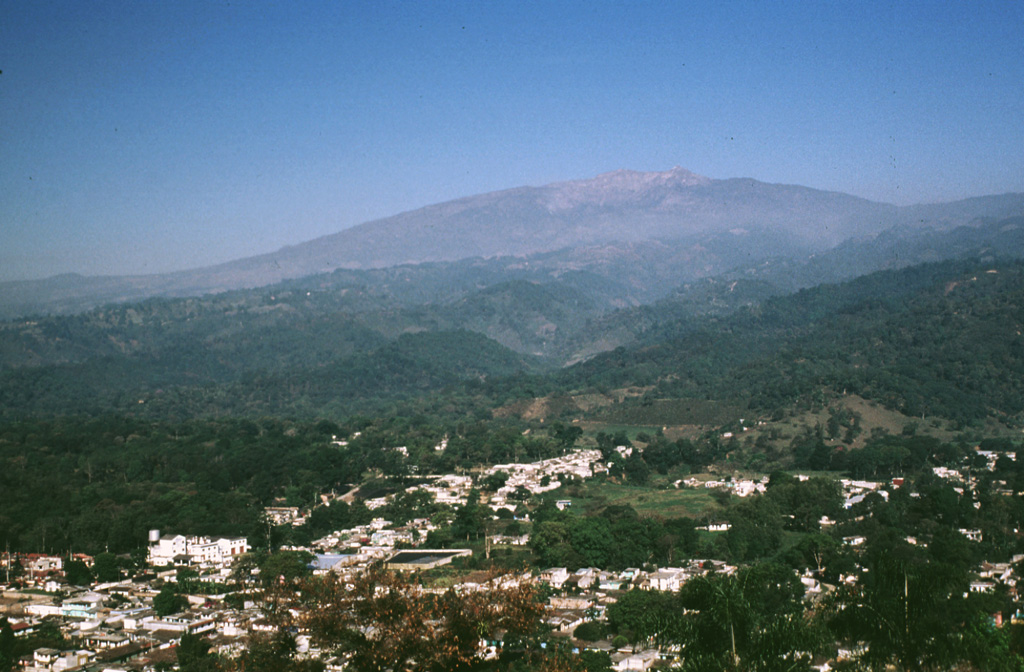 Cofre de Perote volcano towers above the city of Coatepec on its eastern flank. The flanks of contain smaller cones, including the one in the center of the city from which this photo was taken. The volcano was constructed at the eastern margin of the Altiplano and consequently has an asymmetrical profile, extending farther towards the east in the direction of the lower-altitude coastal plain. Photo by Lee Siebert, 1999 (Smithsonian Institution).