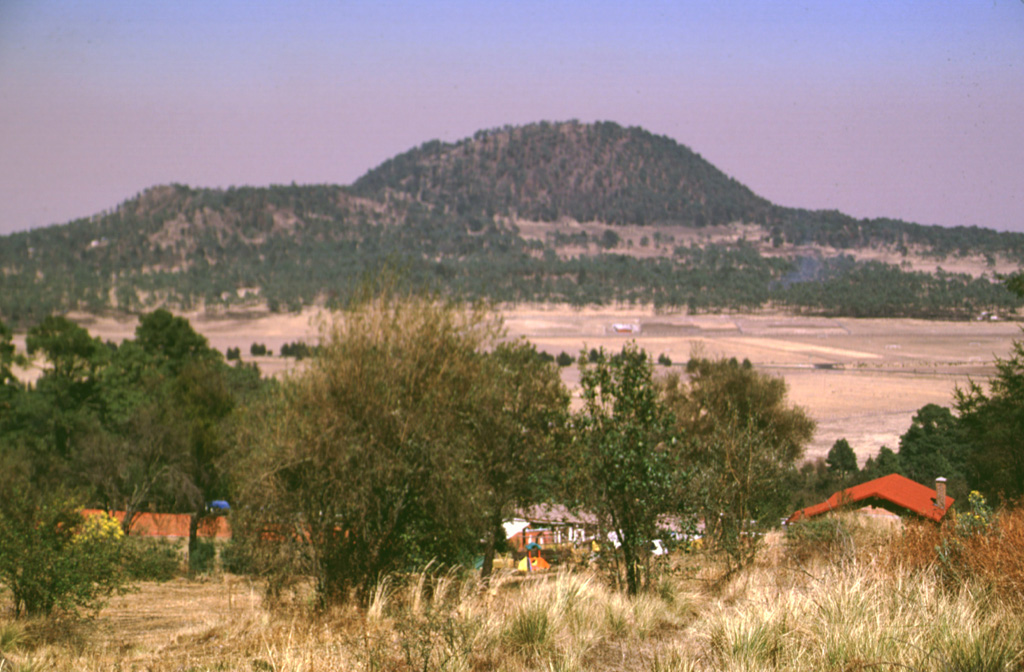 Xitle scoria cone, seen here from the SE, is one of the youngest features of the Chichinautzin volcanic field. The west-flank Xicontle cone, with a 150-m-wide crater, forms the flat ridge to the left. The eruption began about 1,600 years ago producing ashfall that underlies early lava flows. Five flank vents, at Xicontle and on other sides of the Xitle cone, produced voluminous lava flows that surrounded the scoria cone and traveled up to 13 km N, covering 80 km2. Photo by Lee Siebert, 1998 (Smithsonian Institution).