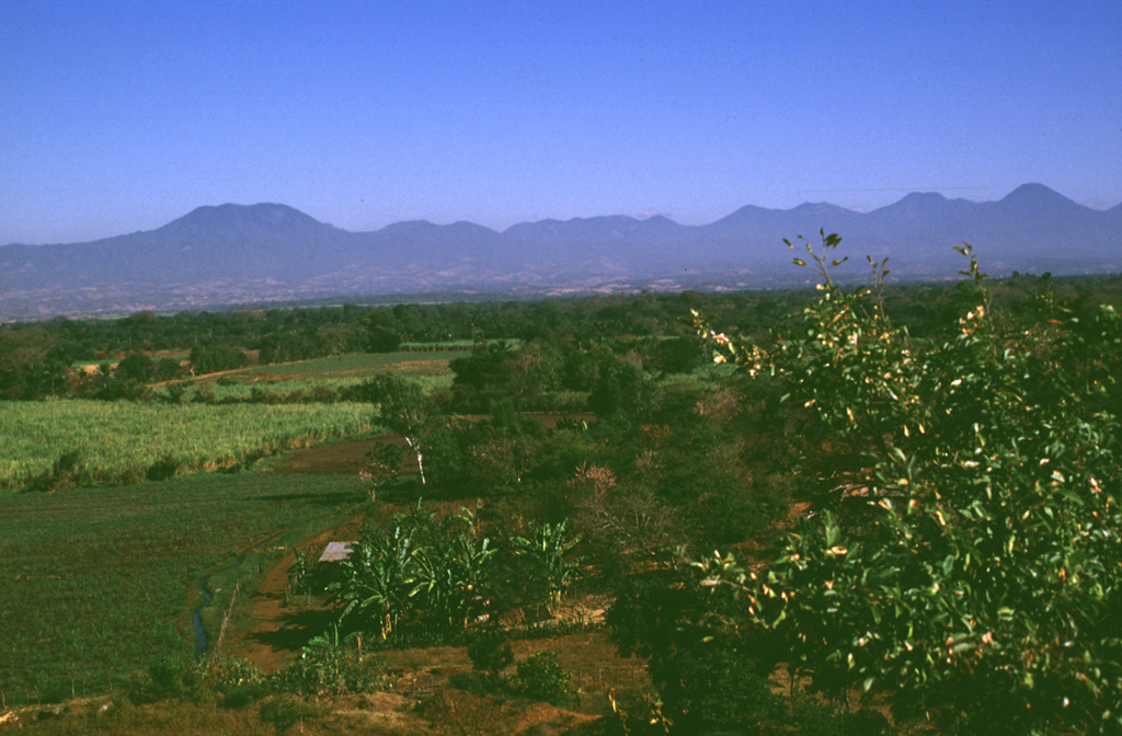 The broad E-W-trending Apaneca Range is seen here from the south with flat-topped Cerro de Apaneca on the left. The Laguna Las Ninfas -Laguna Verde complex is in the center, and to its right are Cerro Cuyanausul, Cerro los Ranas, Cerro el Aguila, and Cerro los Naranjos. The Concepción de Ataco caldera lies beyond the center horizon, behind post-caldera cones. The photo is taken from the top of a hummock on the surface of the massive Acajutla debris avalanche deposit that originated from Santa Ana volcano, which is out of view to the right. Photo by Lee Siebert, 1999 (Smithsonian Institution).