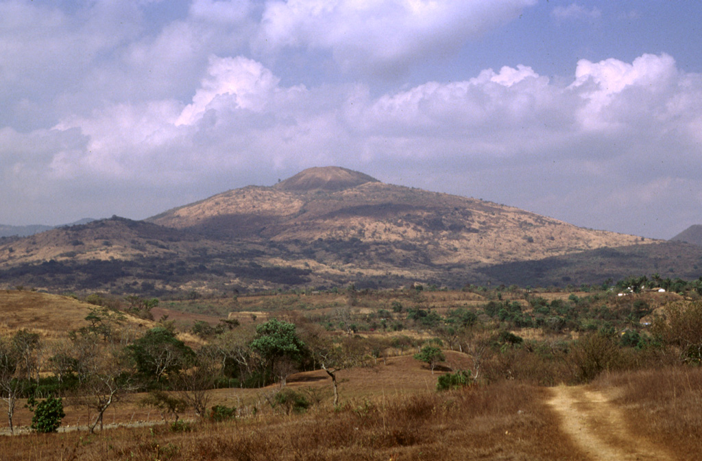 Volcán de Flores, seen here from the SSW, is one of the largest of a cluster of small volcanoes located behind the main volcanic front in SE Guatemala. The summit rises up to 600 m above a basement of Cretaceous and Tertiary sedimentary rocks and contains a smaller summit cone with a shallow crater that opens to the east. An alignment of scoria cones trends across the flanks. Photo by Francesco Frugioni, 1999 (Istituto Nazionale di Geofisca e Vulcanologia, Rome).