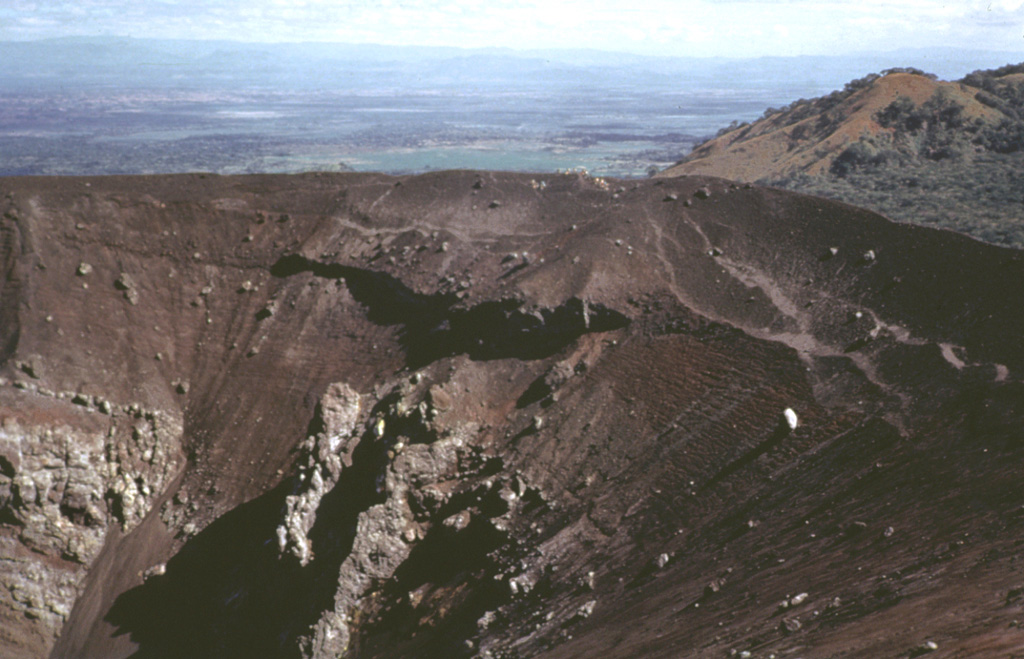 Volcán Tecolote is one of the youngest scoria cones of the Pinacate volcanic field and is located NE of Cráter Elegante. This complex cone contains faults and small craters, opens towards the NW, and was constructed on top of the Mayo cone. Large volcanic bombs, some with cores of older volcanic and non-volcanic rocks, are scattered across the southern and east crater rims and southern flanks. Six basaltic ‘a’a lava flows extend from the base of the cone. Photo by Bill Rose, 1974 (Michigan Technological University).