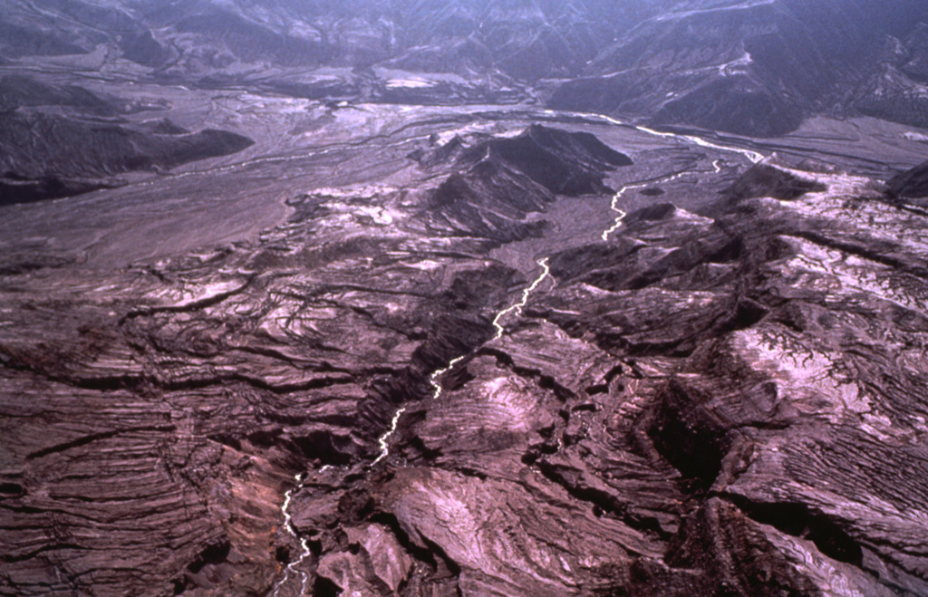 Devastating pyroclastic flows and surges from the March-April 1982 eruptions of El Chichón turned large areas surrounding the crater into a landscape devoid of vegetation. The pyroclastic flows and surges travelled radially away from the volcano to distances of about 6 km, covering an area of about 153 km2. This January 1983 aerial photo shows the effect of extensive erosion of these deposits during the previous rainy season. Photo by Bill Rose, 1983 (Michigan Technological University).