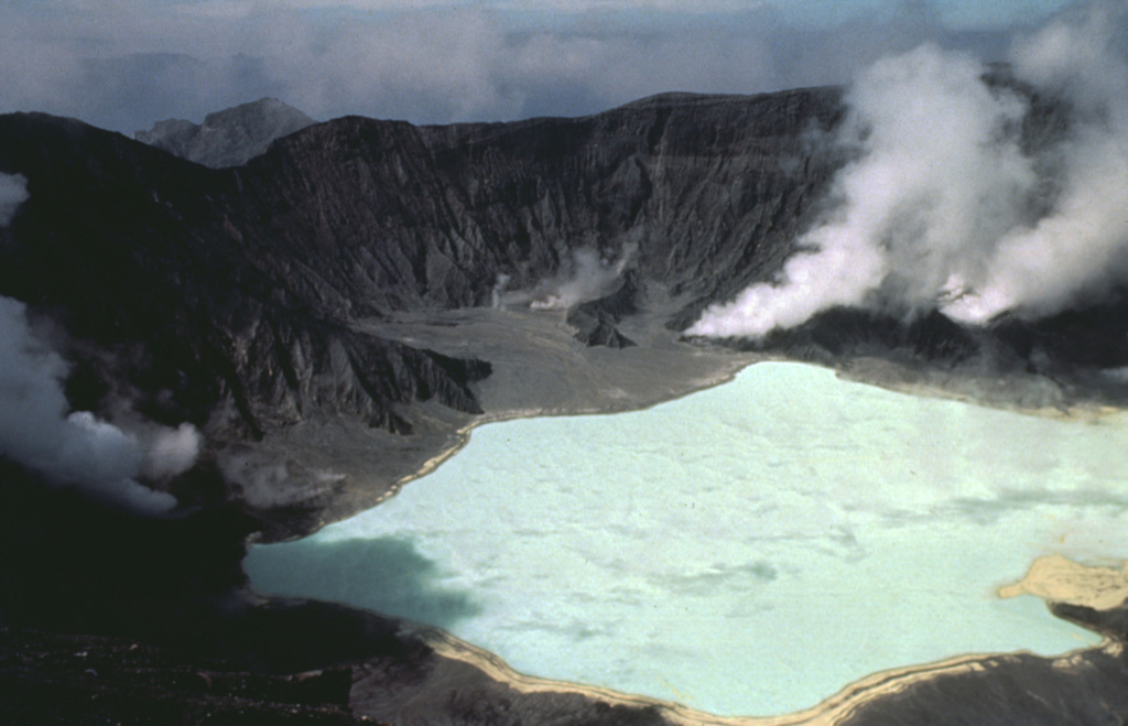 The  new 1-km-wide El Chichón crater is seen here in January 1983, less than a year after the major explosive eruption . By this time it was partially filled by a hot, acidic lake. The isolated, low-profile, volcano is a small lava dome complex that was heavily vegetated prior to 1982. More than a half-dozen large explosive eruptions have occurred since the mid-Holocene. Photo by Bill Rose, 1983 (Michigan Technological University).