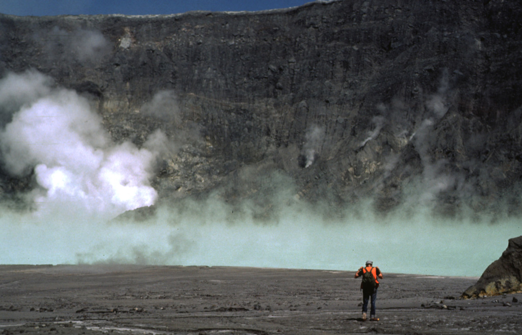 A volcanologist traverses the floor of the El Chichón crater toward the steaming, turquoise crater lake in January 1983, during the first visit to the crater following the major March-April 1982 explosive eruption. The new lake had grown to a depth of about 120 m by November 1982, after which lake level dropped slightly. In January 1983 the lake was hot (52-58°C) and acidic (pH of 0.5). By October 1983 the temperature had dropped to 42°C and the pH was 1.8.  Photo by Bill Rose, 1983 (Michigan Technological University).